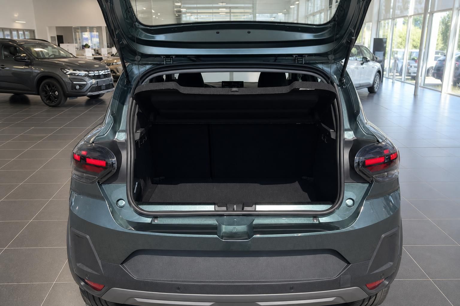Geöffneter Kofferraum eines grauen SUV mit schwarzer Innenausstattung im Autohaus-Showroom
