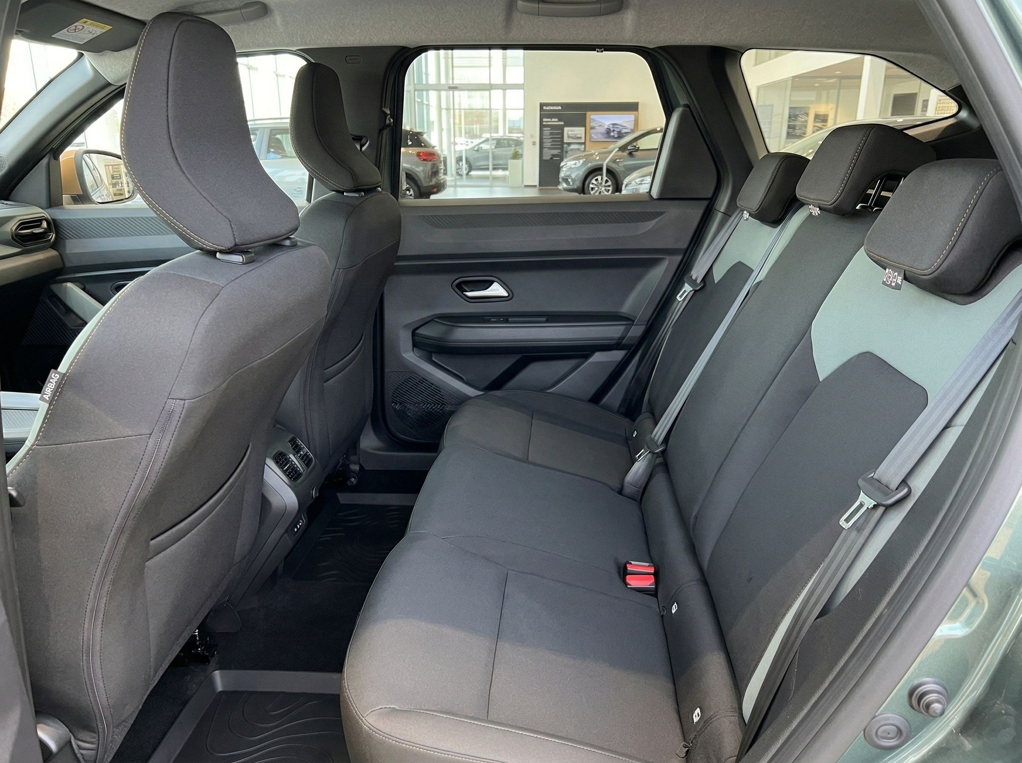 Fahrzeug Rücksitzbereich mit dunkler Stoffausstattung und Sicherheitsgurten