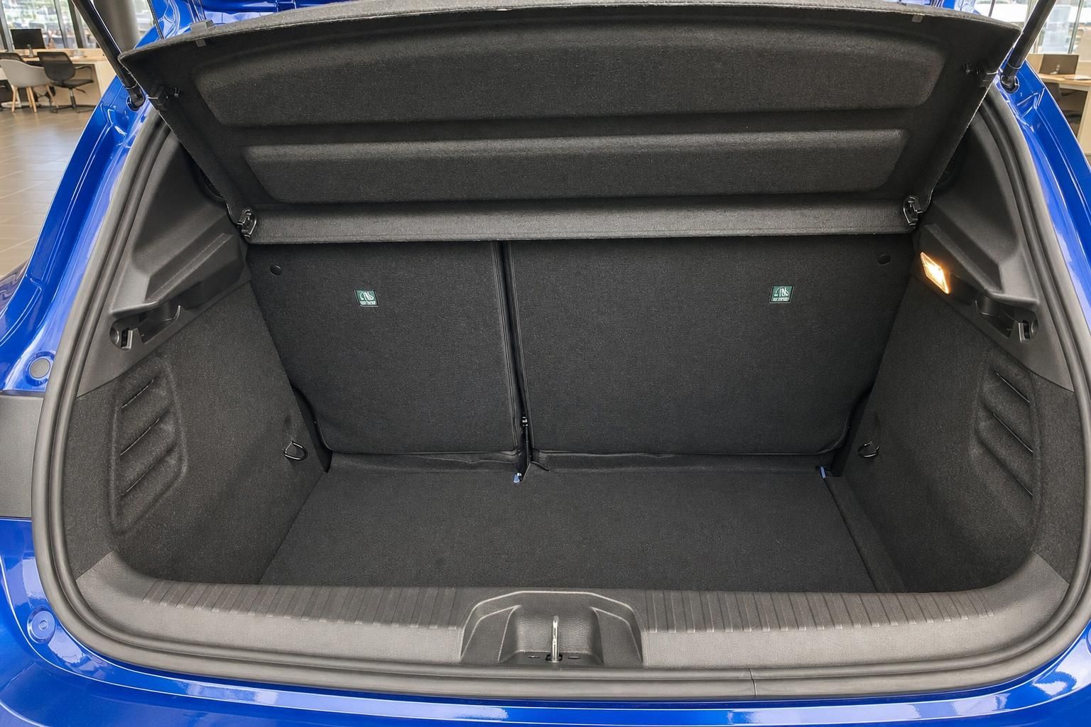 Kofferraum eines blauen Fahrzeugs mit schwarzer Innenverkleidung, geöffnete Heckklappe