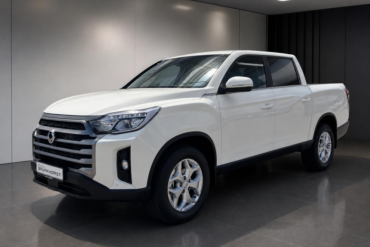 Weißer KGM Pickup 4x4 Seitenansicht in moderner Showroom-Umgebung