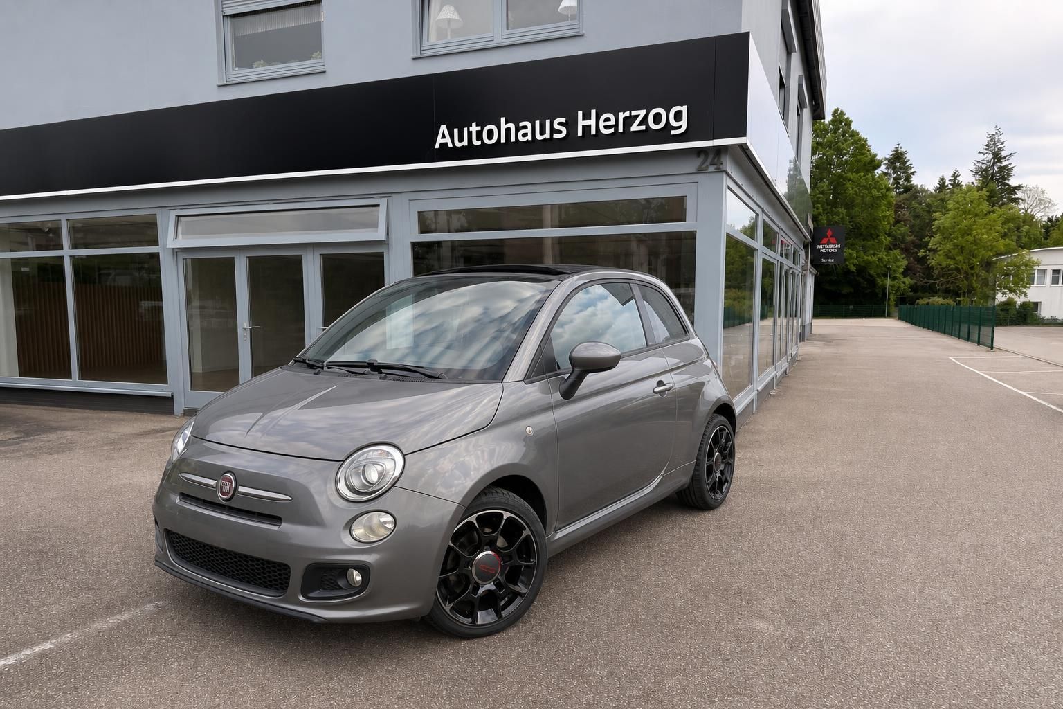 Fiat 500 grau vor Autohaus Herzog Seitenansicht Standaufnahme