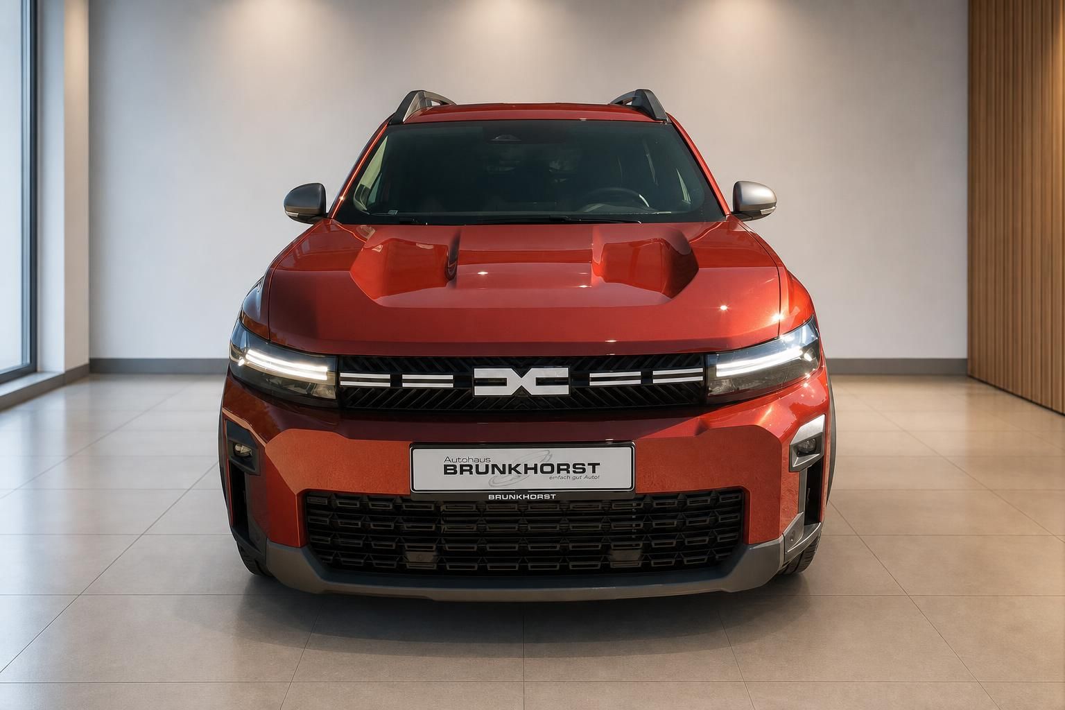 Dacia Bigster orange Frontansicht mit LED-Scheinwerfern im Showroom