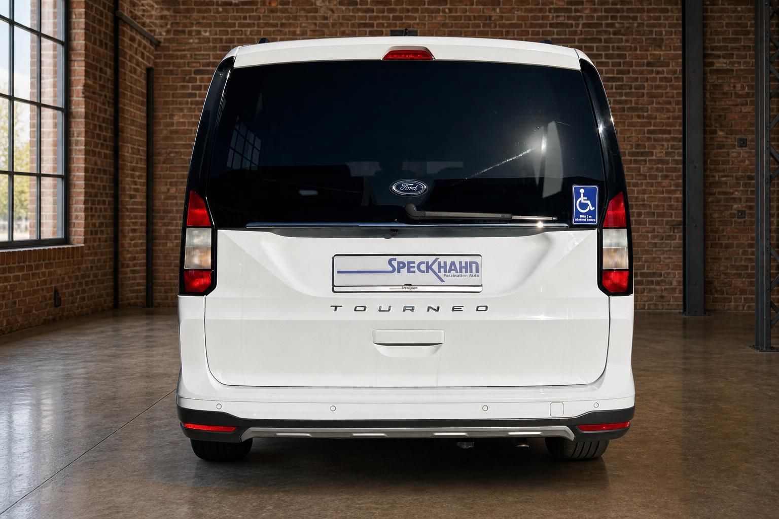 Ford Tourneo weiß Heckansicht in moderner Halle mit Backsteinwand