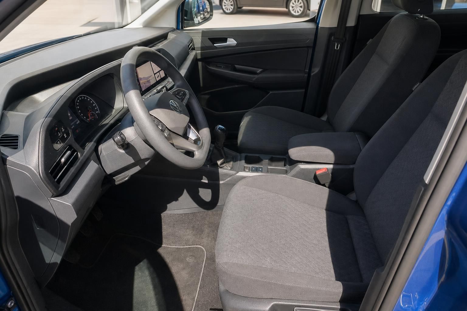 Volkswagen Caddy Innenraum mit grauem Fahrersitz und modernem Cockpit im Autohaus