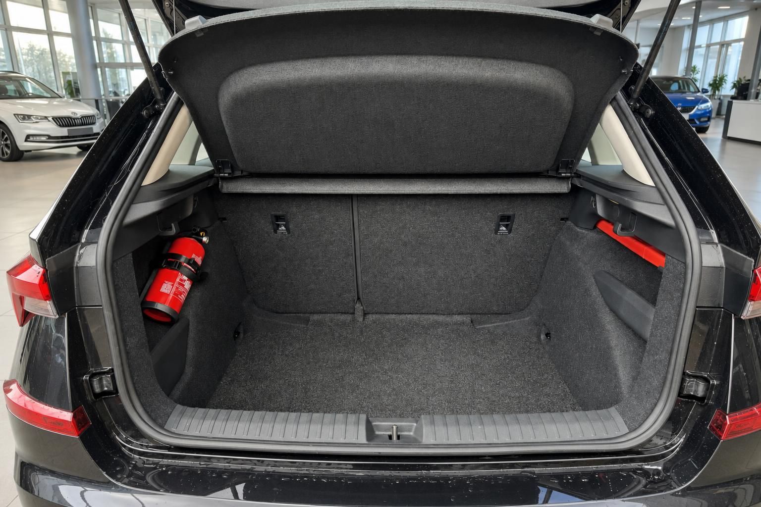 Geräumiger Kofferraum eines schwarzen Fahrzeugs mit geöffneter Heckklappe und Feuerlöscher im Autohaus