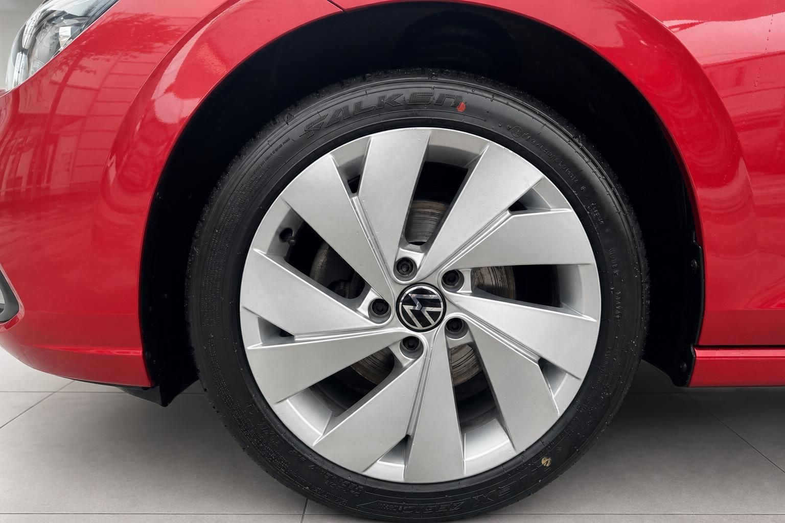 VW Leichtmetallfelge mit Salken-Reifen an rotem Volkswagen – Detailaufnahme Rad