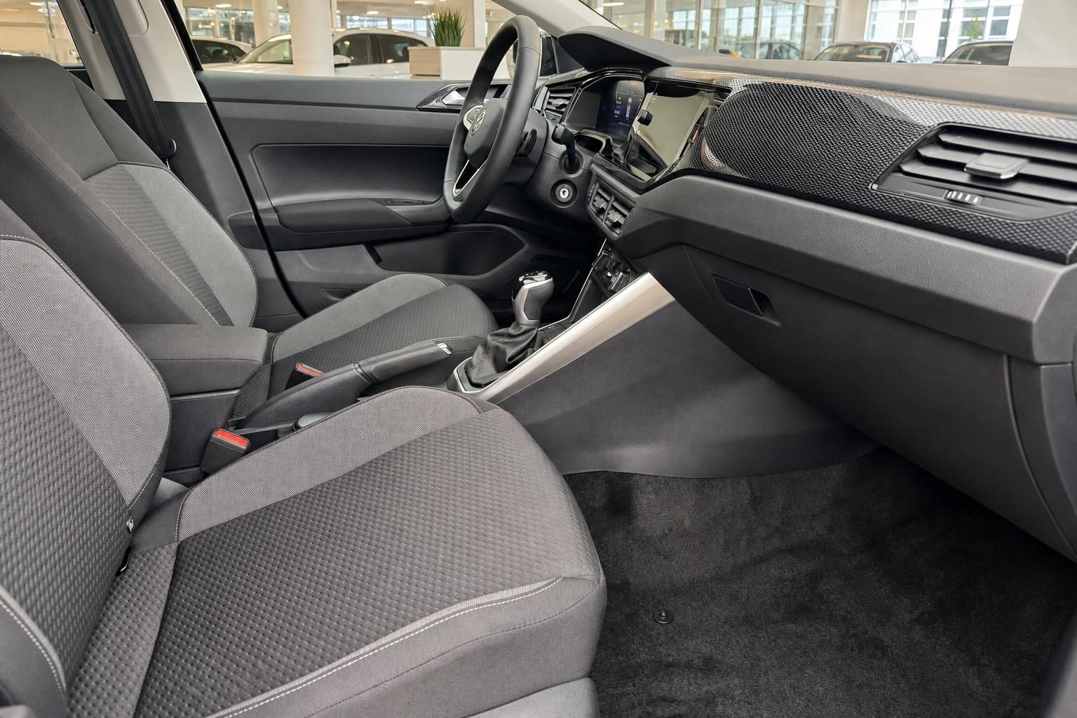 Fahrzeug Innenraum mit grauen Stoffsitzen, Mittelkonsole, Schaltgetriebe und Infotainment-Display