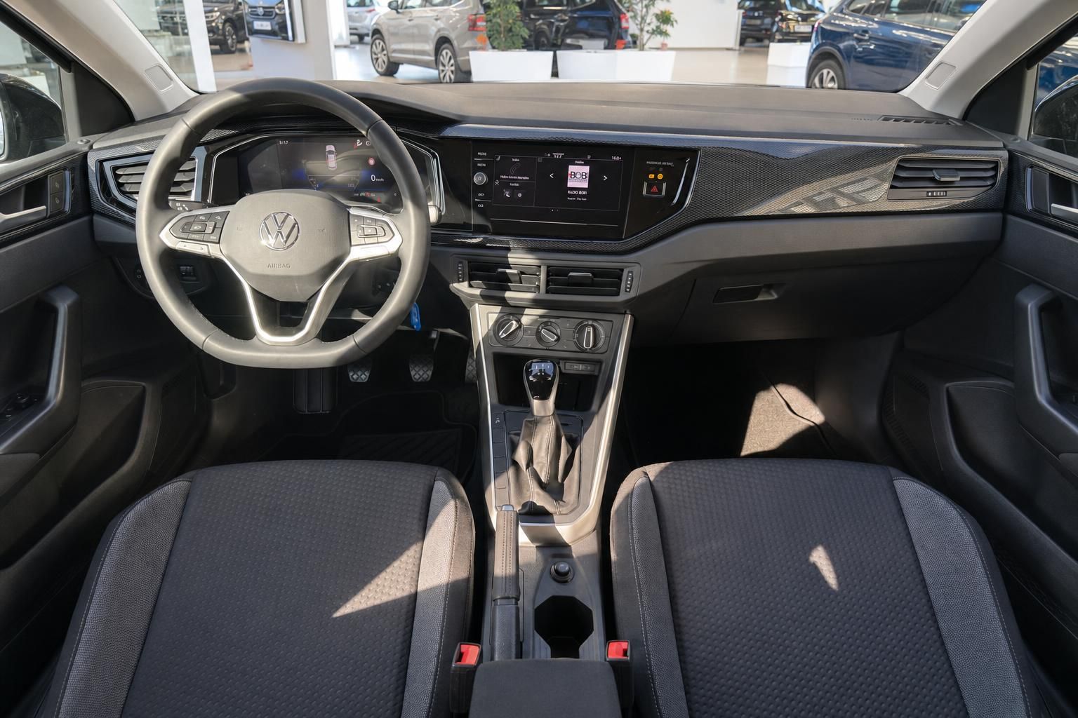 VW Innenraum mit Lenkrad, Digitaltacho, Touchscreen, Mittelkonsole und Vordersitzen in grauem Stoff