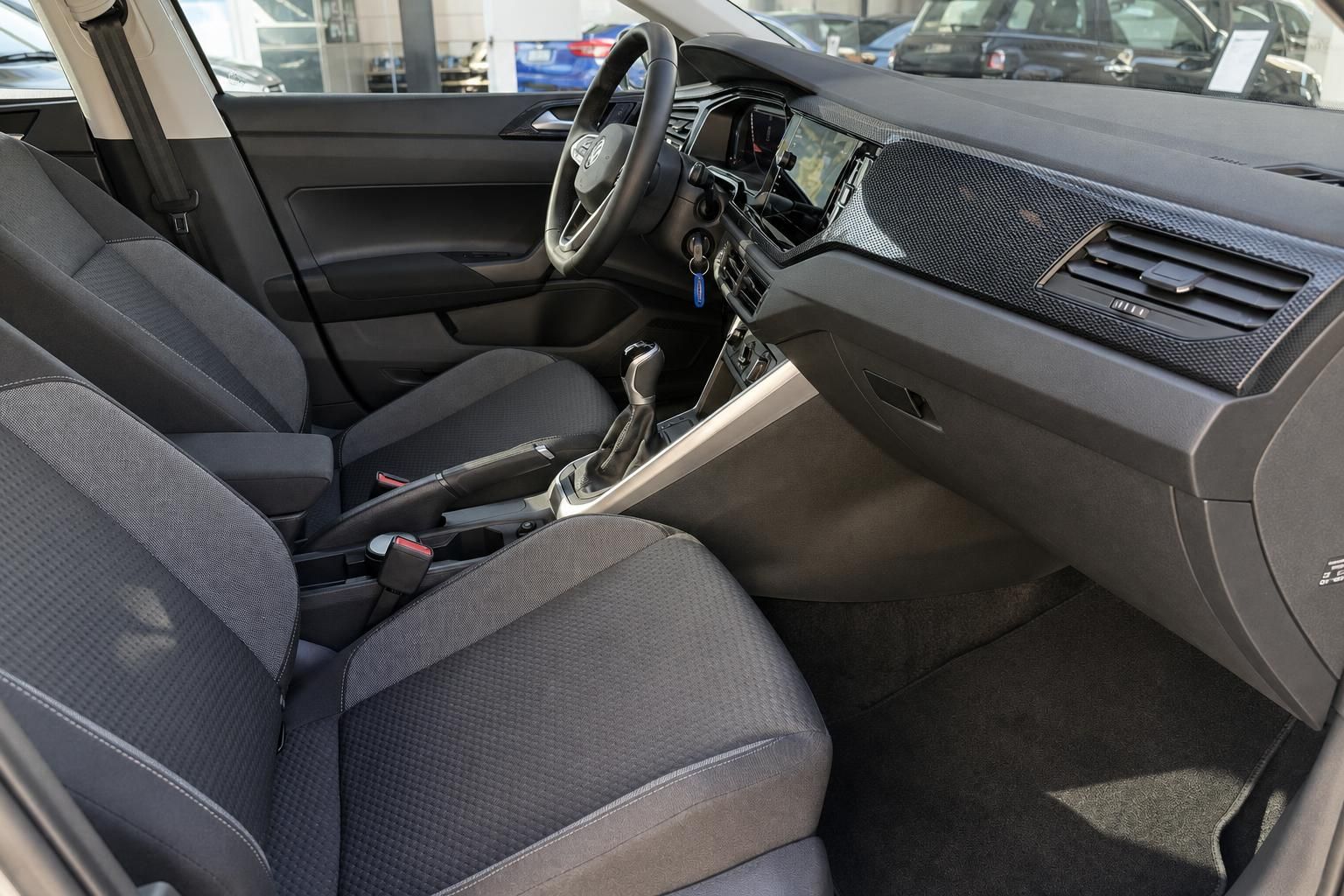 VW Innenraum mit Fahrer- und Beifahrersitz, Automatikgetriebe, Lenkrad und Infotainment-Display