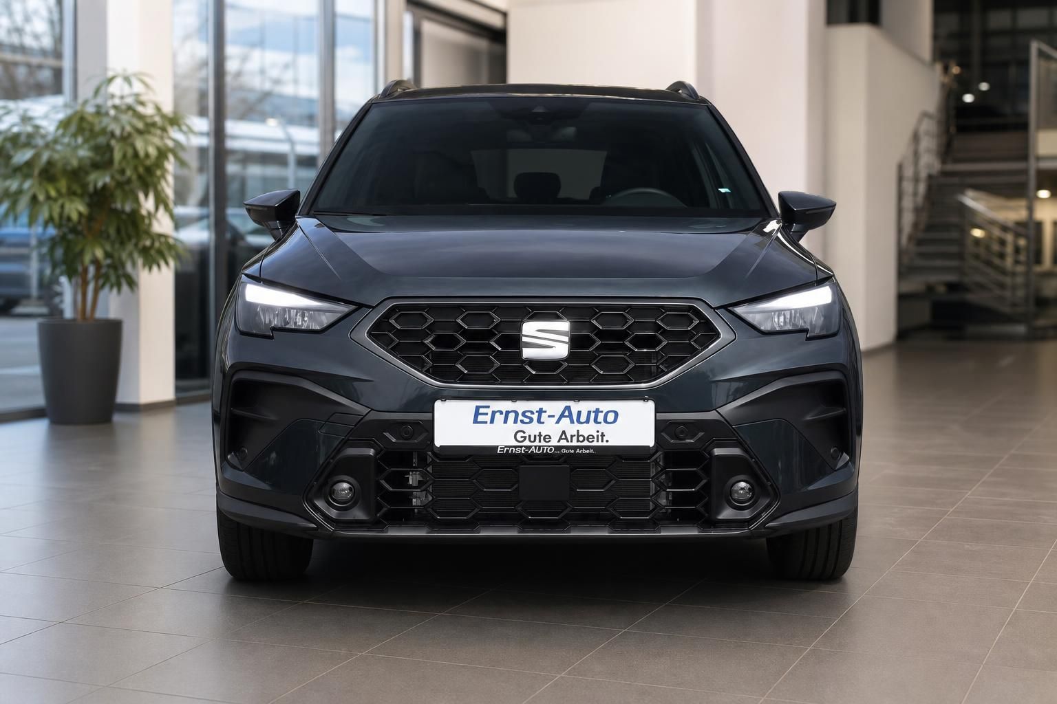 Dunkelgrauer SEAT SUV Frontansicht mit Kühlergrill und LED-Scheinwerfern im Waldweg