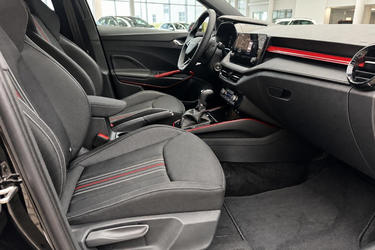 Fahrzeuginnenraum mit schwarzen Sportsitzen, roten Akzenten, Mittelkonsole und Touchscreen-Infotainmentsystem