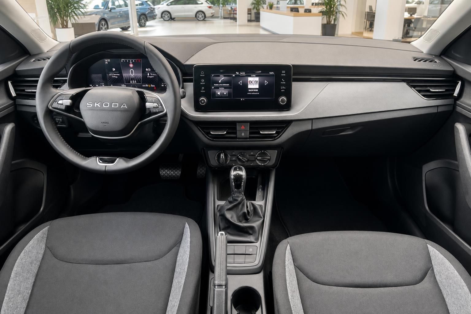 Skoda Innenraum mit Lenkrad, Touchscreen-Infotainment und grauem Stoffsitzen – modernes Cockpit
