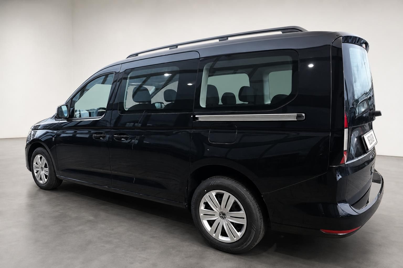 VW Caddy Van in Dunkelblau, Seitenansicht von hinten im Fotostudio