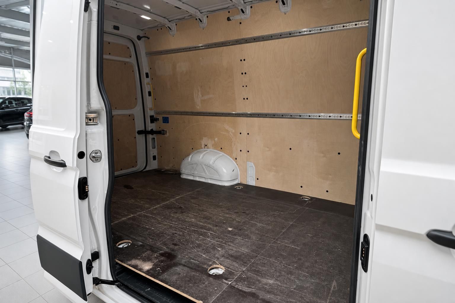 Laderaum eines weißen Transporters mit Holzverkleidung, Ladestreben und dunklem Bodenbelag
