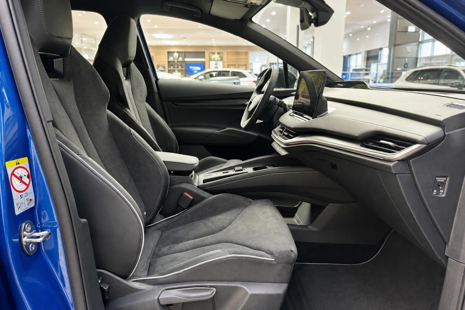 Innenraum mit schwarzen Sportsitzen, Lenkrad und Touchscreen-Display im blauen Fahrzeug