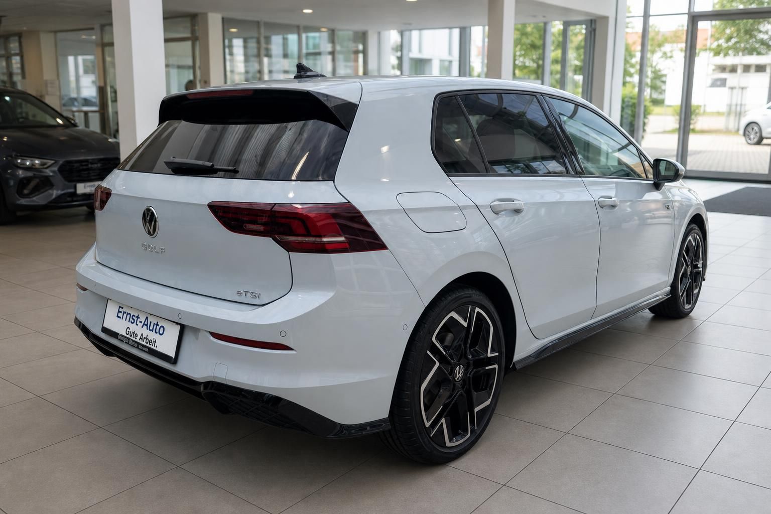 VW Golf 8 eTSI weiß Heckansicht im Autohaus – sportliche Felgen, schwarzer Dachspoiler