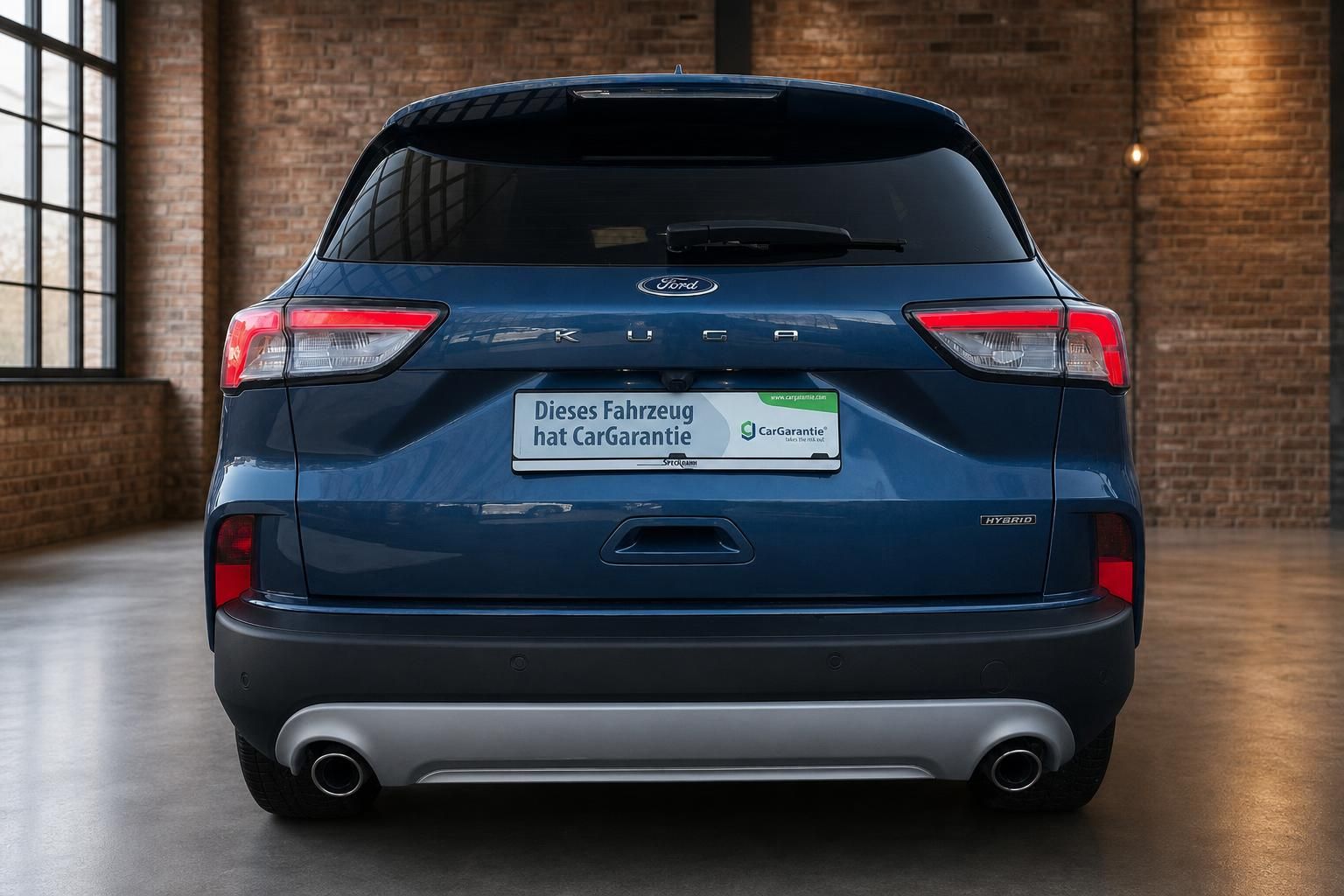 Ford Kuga Hybrid blau Heckansicht in Halle mit Backsteinwand