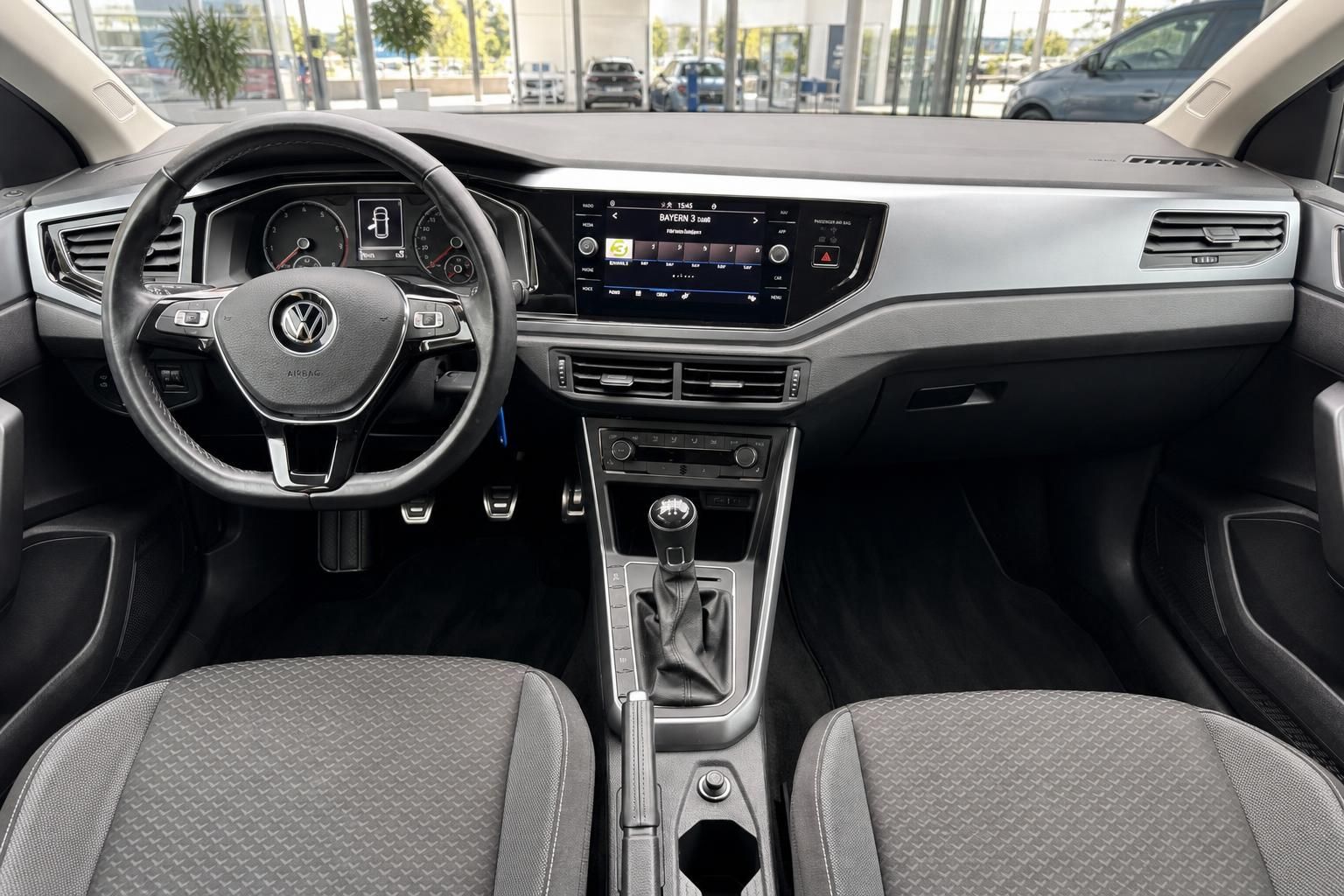 VW Polo Innenraum – Cockpit mit Lenkrad, Touchscreen, Schaltgetriebe und grauen Stoffsitzen