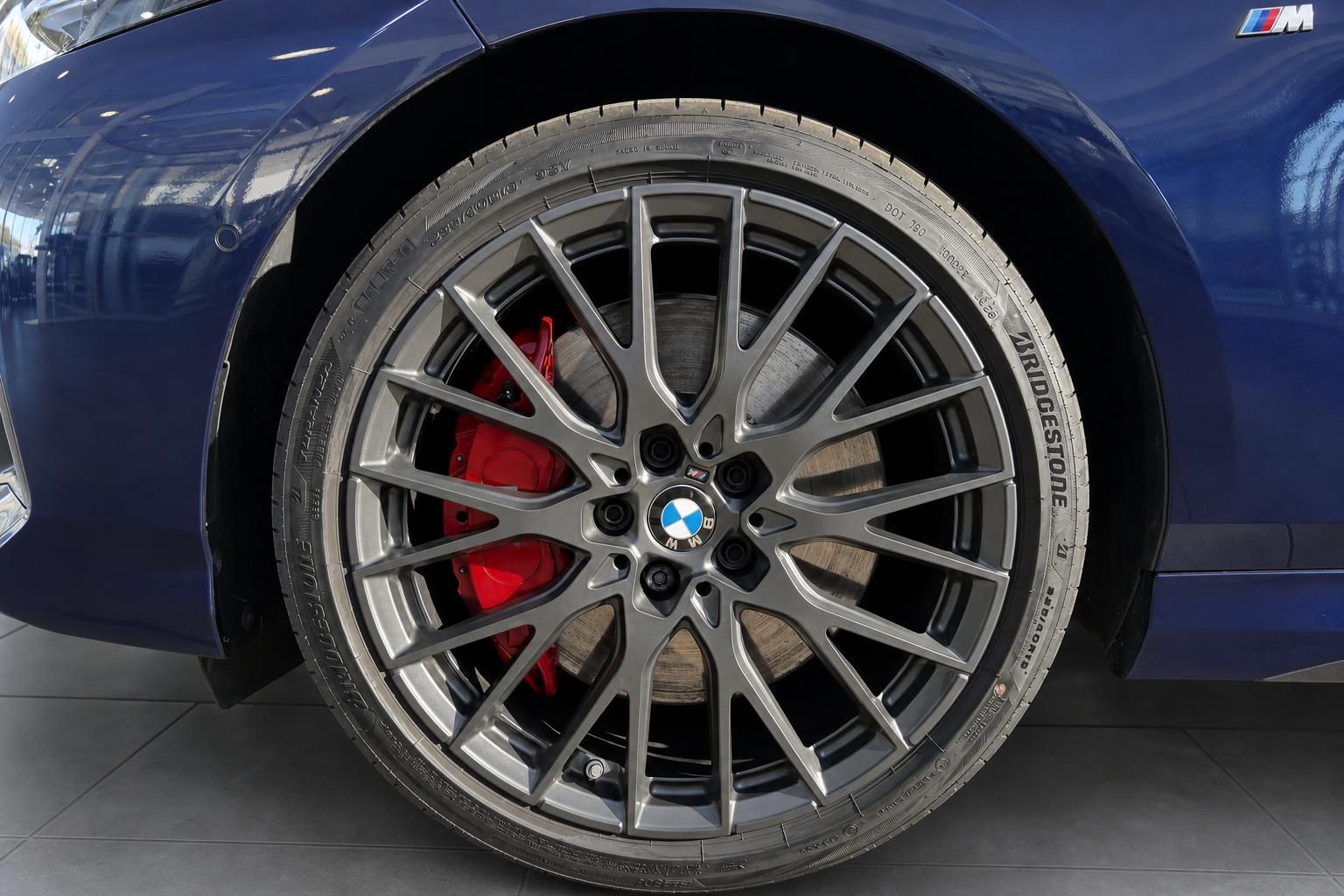 BMW M Leichtmetallfelge mit roten Bremssätteln und Bridgestone-Reifen an blauem BMW