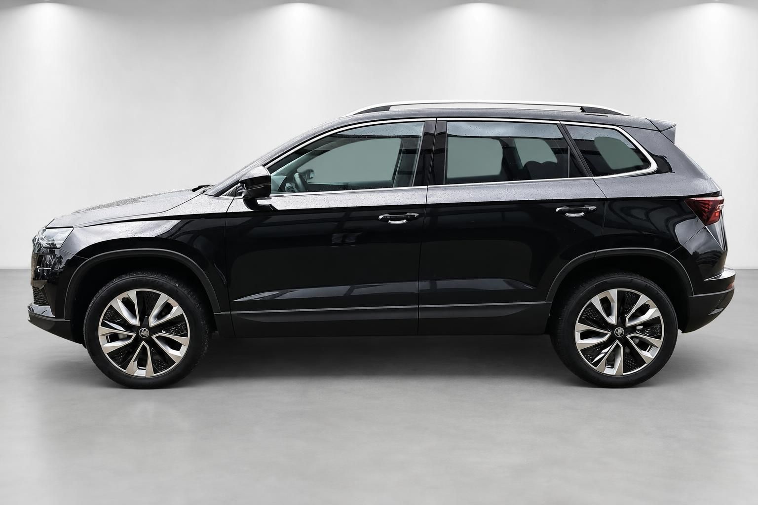 Schwarzes SUV im Seitenprofil im Studio, glaenzende Lackierung und Leichtmetallfelgen