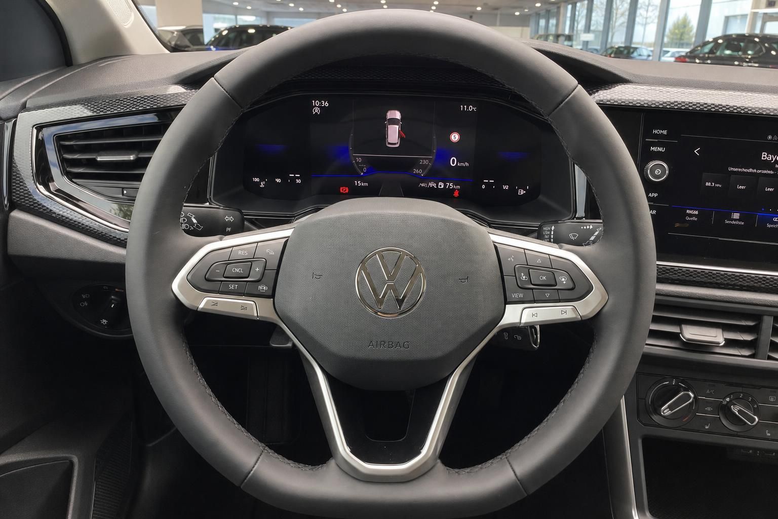 VW Lenkrad mit Multifunktionstasten und digitalem Cockpit im Fahrzeuginnenraum