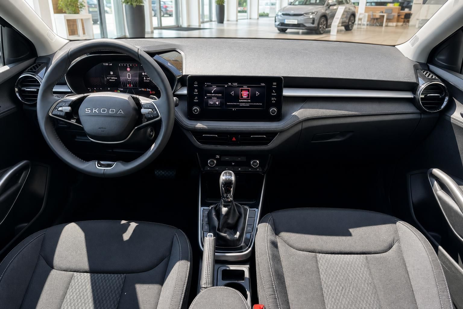 Skoda Innenraum mit Lenkrad, Infotainment-Display und Schaltgetriebe – modernes Cockpit in Schwarz-Grau