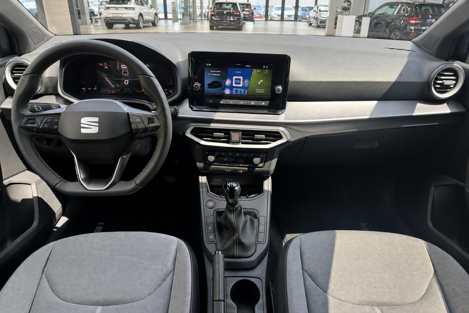 SEAT Innenraum mit Lenkrad, Infotainment-Display, Schaltgetriebe und grauen Stoffsitzen