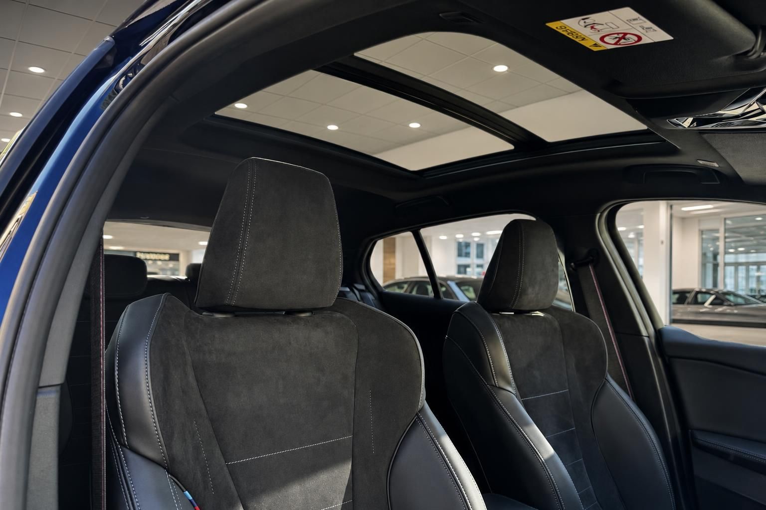 BMW Innenraum mit schwarzen Leder-Alcantara Sitzen und großem Panorama-Glasdach im Autohaus