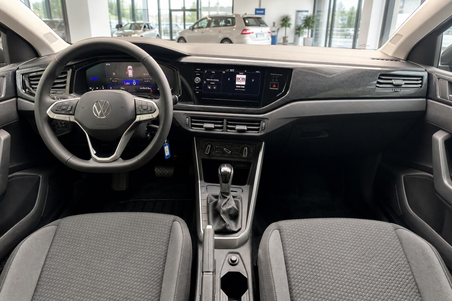 VW Innenraum Cockpit mit Lenkrad, Infotainment-Display, Schaltgetriebe und grauen Stoffsitzen
