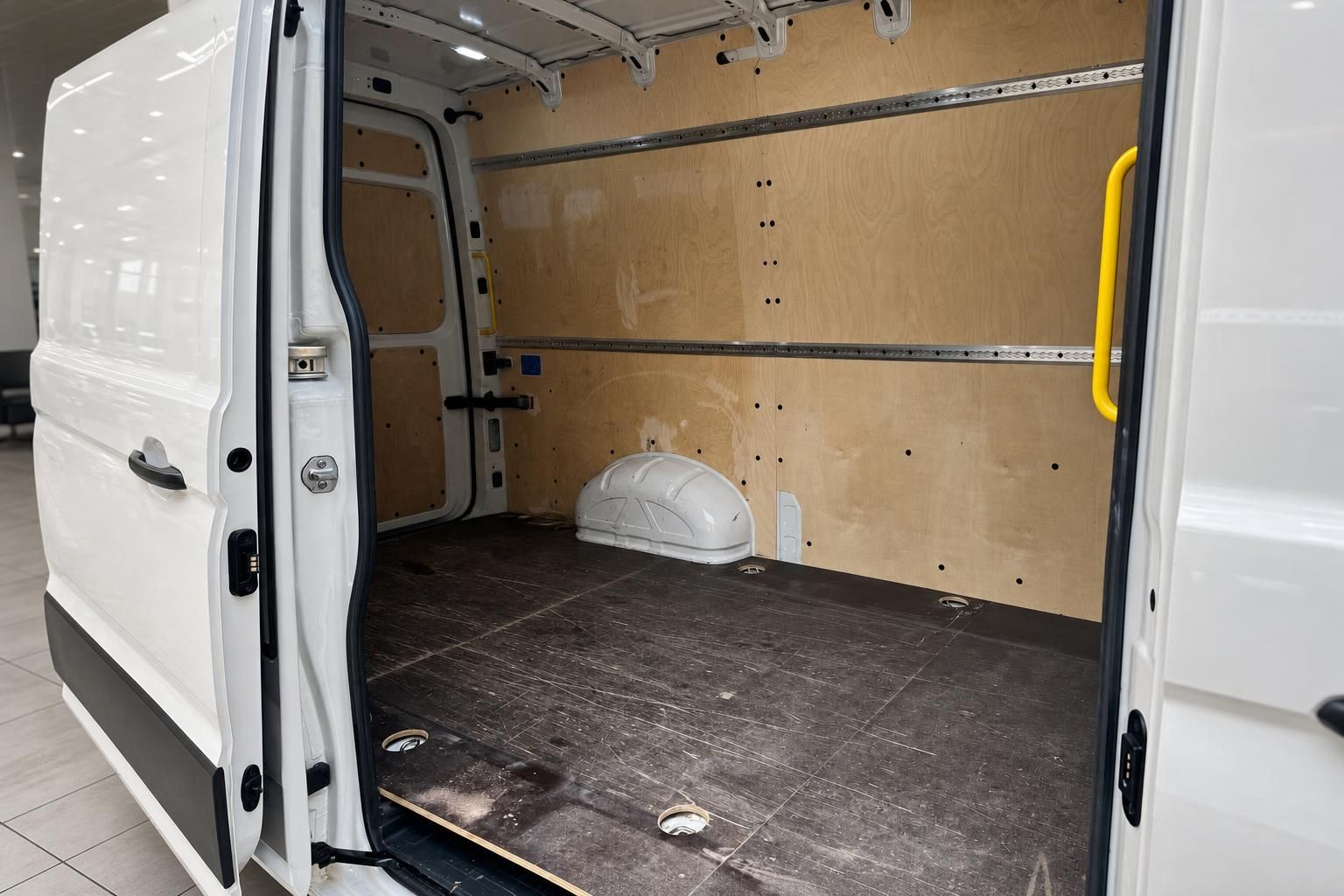 Laderaum eines weißen Transporters mit Holzverkleidung, dunklem Boden und gelbem Haltegriff