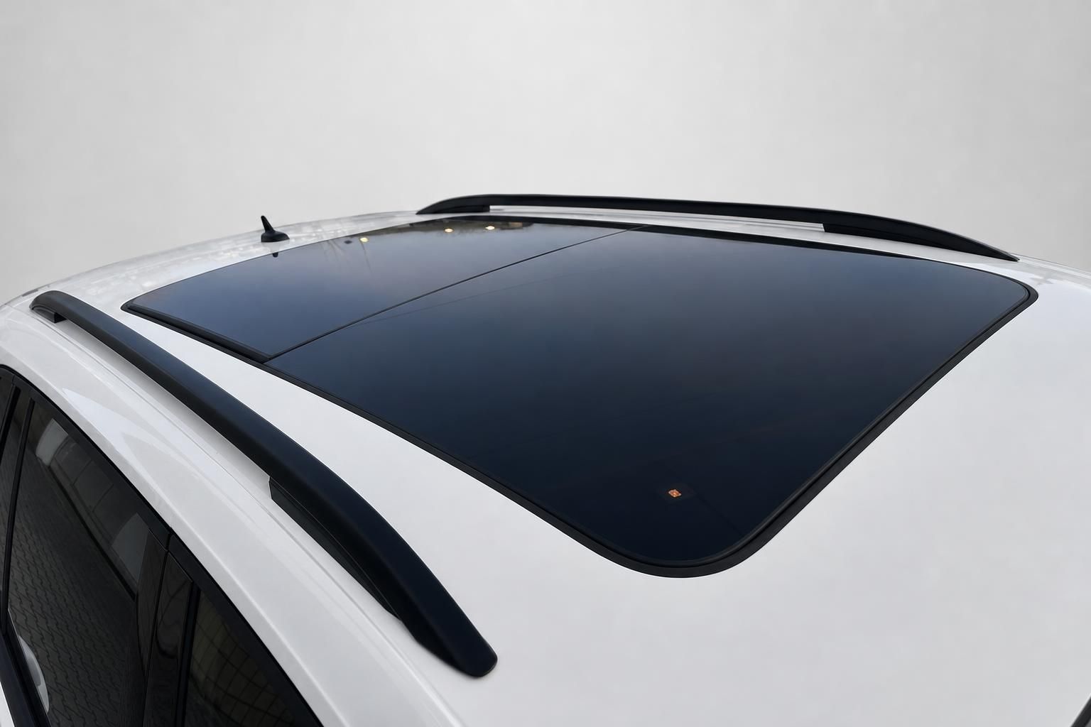 Panorama-Glasdach eines weißen SUV mit schwarzen Dachreling-Details – Detailansicht von oben